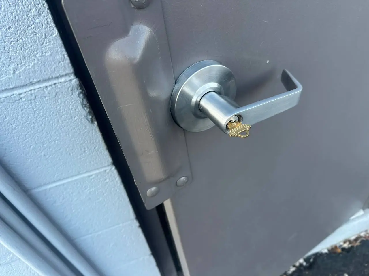 Commercial locksmith repairing storefront door lock and checking security system in a business location in Bowling Green Kentucky